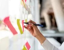 business woman writing on sticky notes on a board