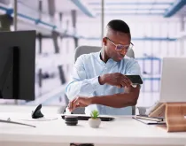 man checking blood glucose monitor at desk