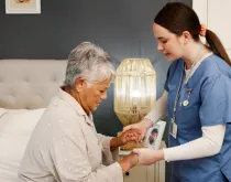 nurse helping senior woman patient in bed