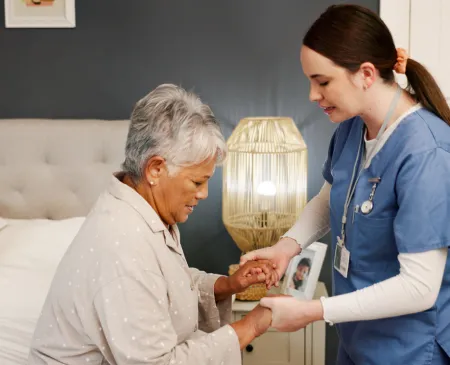 nurse helping senior woman patient in bed