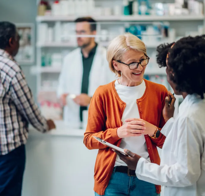 African american woman pharmacist talking to a senior customer in a pharmacy
