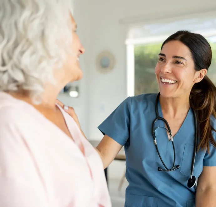 Happy female doctor talking to a senior woman on a house call